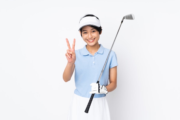 Młoda Wietnamska Golfista Kobieta Nad Odosobnioną Biel ścianą Uśmiecha Się Zwycięstwo Znaka I Pokazuje