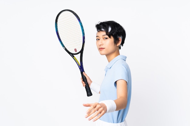 Młoda Wietnamska gracz w tenisa kobieta nad odosobnioną biel ścianą bawić się tenisa