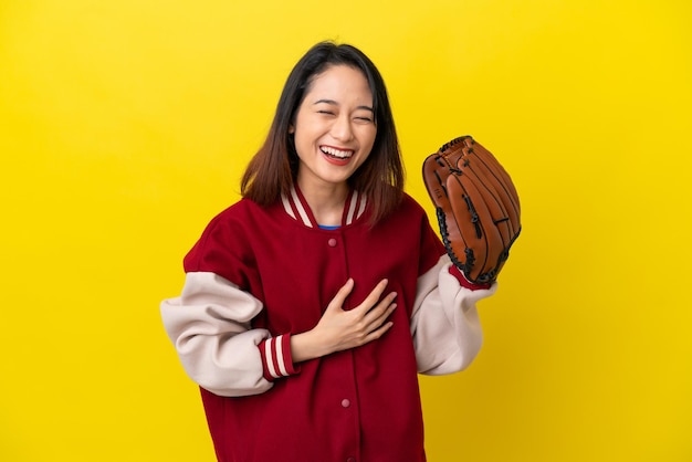 Młoda wietnamska kobieta z rękawicą baseballową odizolowaną na żółtym tle często się uśmiecha