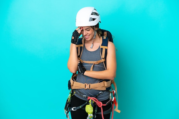 Młoda włoska kobieta rockclimber odizolowana na niebieskim tle, śmiejąc się