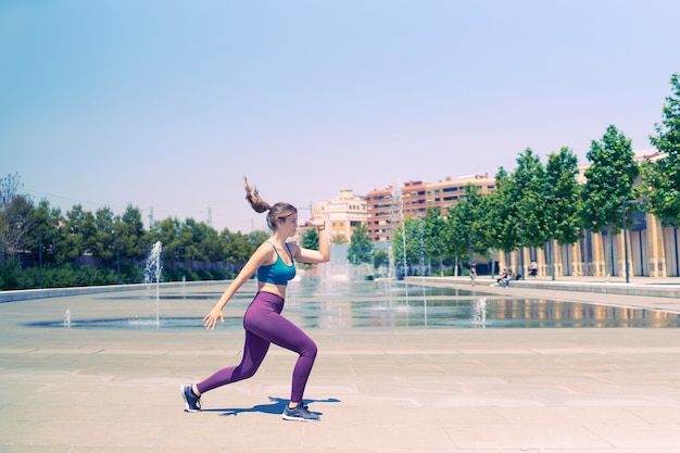 Zdjęcie młoda wysportowana dziewczyna ćwicząca cardio pośrodku miejskiego parku bez ludzi wokół koncepcji zdrowego stylu życia