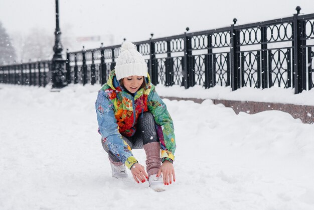 Młoda wysportowana dziewczyna zawiązuje buty w mroźny i śnieżny dzień. Fitness, bieganie.