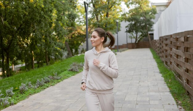 Młoda wysportowana kobieta w odzieży sportowej ćwiczy poranny jogging na świeżym powietrzu w parku