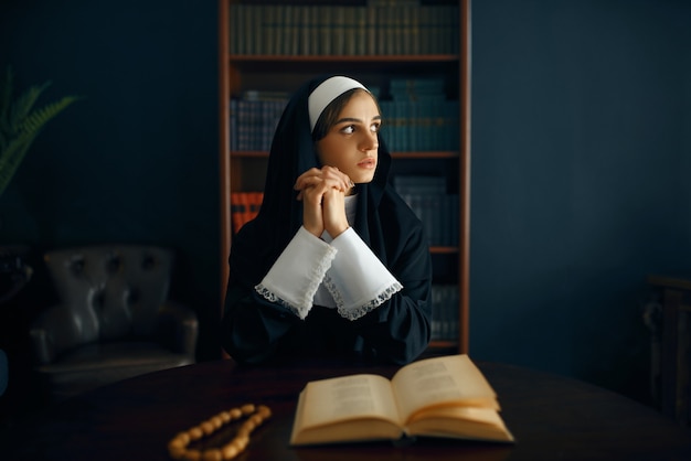Młoda zakonnica w sutannie modli się ze skrzyżowanymi ramionami. Siostra w klasztorze, religia i wiara, osoba religijna