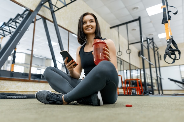 Młoda zdrowa kobieta odpoczywa w gym z butelki wodą