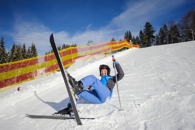 Młoda żeńska narciarka po spadku na halnym skłonie
