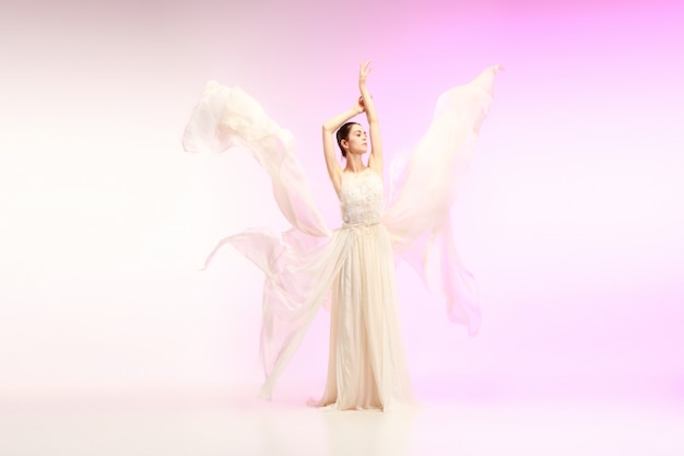Młoda zgrabna tancerka baletowa lub klasyczne baleriny taniec w studio różowy. Kaukaski model na pointach