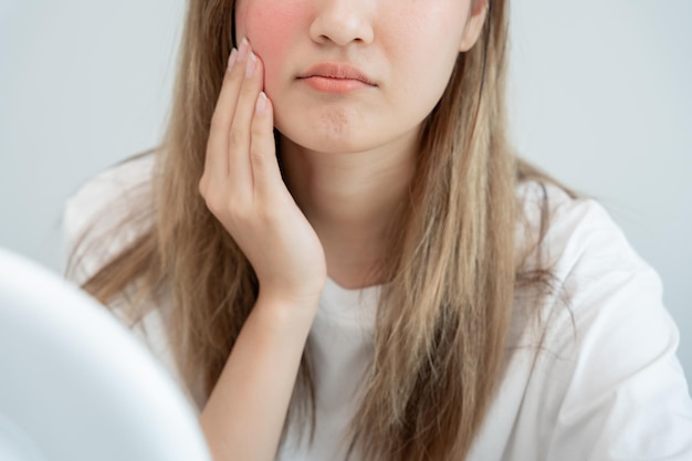 Młode azjatyckie kobiety martwią się o twarz Dermatologia i alergia na sterydy w kosmetykach wrażliwa skóra czerwona twarz od oparzeń słonecznych trądzik alergiczny na chemikalia wysypka na twarzy problemy skórne i piękno