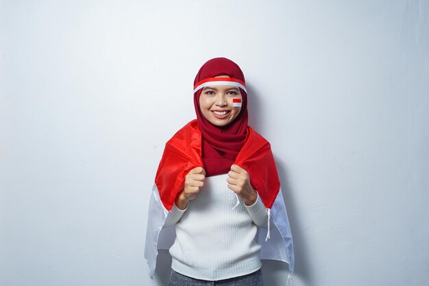 Młode azjatyckie muzułmanki świętują dzień niepodległości Indonezji trzymając czerwono-białą flagę