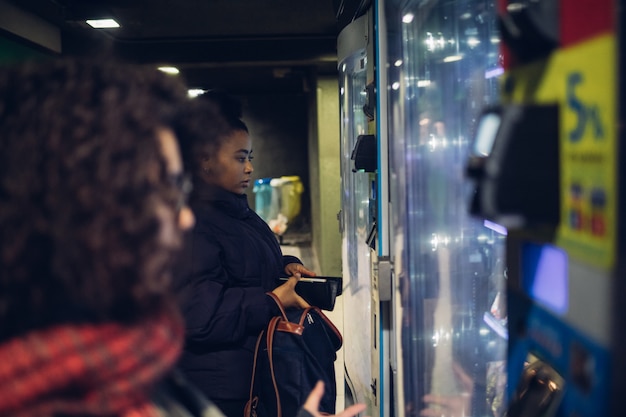 Zdjęcie młode brunetki dziewczyny patrząc automat