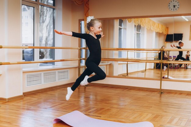 Młode dziewczyny robiące ćwiczenia gimnastyczne lub ćwiczące na zajęciach fitness