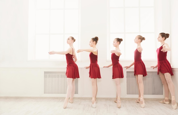 Młode dziewczyny tańczą balet w studio. Taniec choreografowany przez grupę pełnych wdzięku, ładnych, młodych baletnic ćwiczących na zajęciach przed występem. Szkoła tańca klasycznego