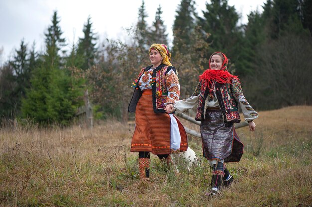 Zdjęcie młode dziewczyny w huculskich strojach chodzą po karpatach.