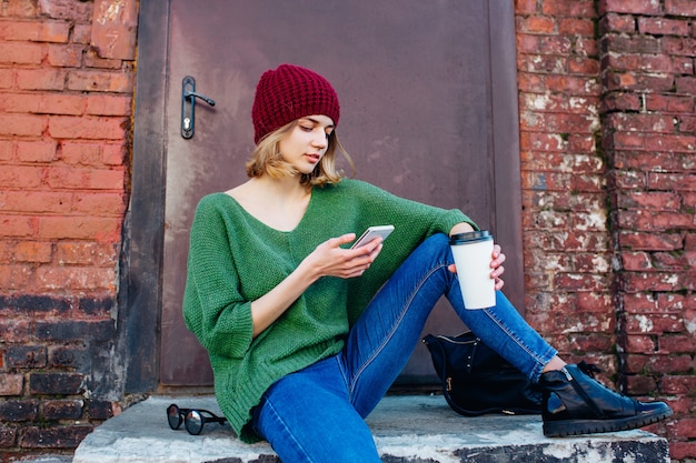 Młode kobiety texting wiadomość na telefonie komórkowym w mieście. Koncepcja stylu życia