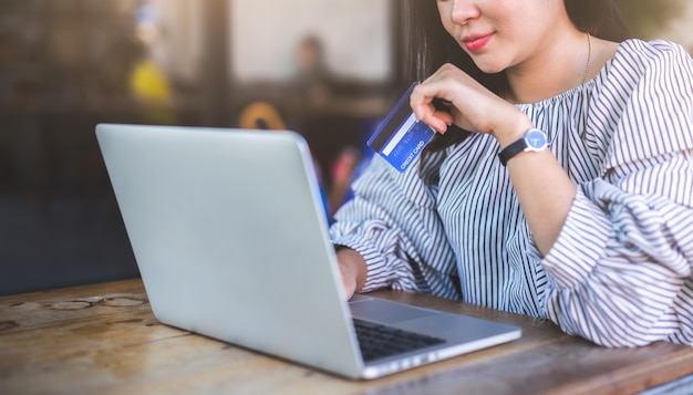 Zdjęcie młode kobiety trzyma kredytową kartę i używa laptop