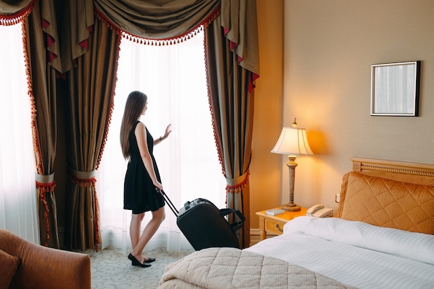 Młode kobiety z walizką zostają w pokoju hotelowym