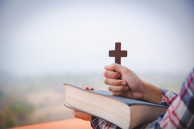 Młode modlące się kobiety ręce z drewnianym krzyżem i świętą Biblią koncepcja religii
