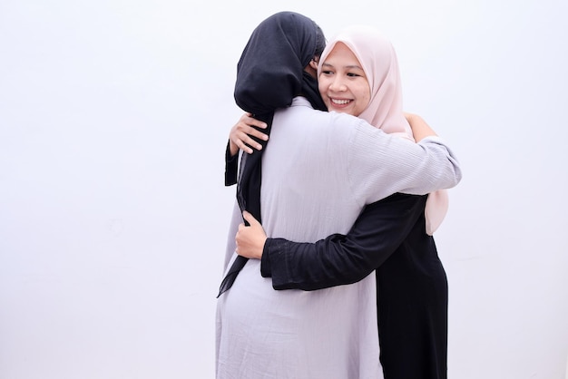 Młode muzułmańskie kobiety w hidżabie przytulają się i uśmiechają. Koncepcja Eid Mubarak.