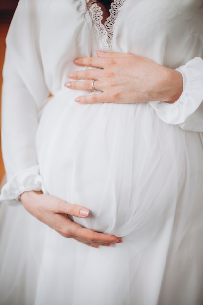 Młode piękne kobiety w ciąży trzymają się za brzuch