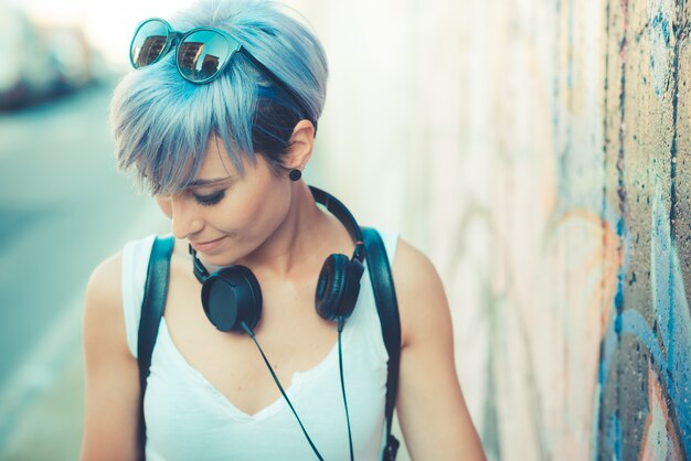 młode piękne krótkie niebieskie włosy hipster kobieta z muzyką słuchawki