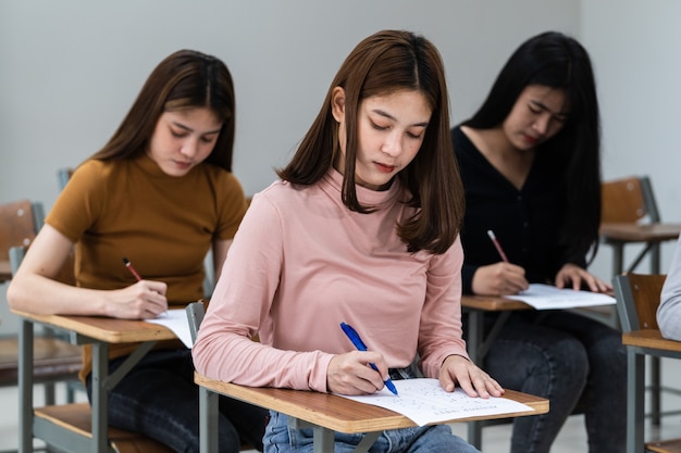 Młode Studentki Uniwersytetu Koncentrują Się Na Egzaminowaniu W Klasie. Uczennice Poważnie Pisze ćwiczenia Z Egzaminów W Klasie.