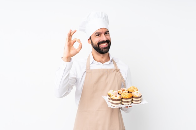 Młodego człowieka mienia muffin tort pokazuje ok znaka z palcami