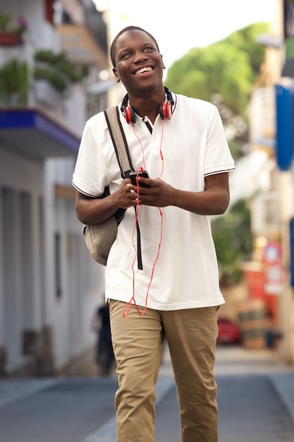 Młodego człowieka odprowadzenie na ulicie z torbą i telefonem komórkowym