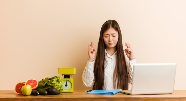 Młodego Dietetyka Chińska Kobieta Pracuje Z Jej Laptopem Krzyżuje Palce Dla Mieć Szczęście
