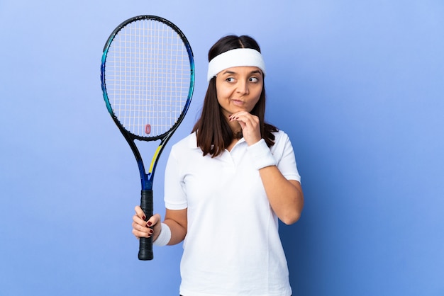 Młodej kobiety gracz w tenisa nad odosobnionym tłem ma wątpliwości i główkowanie