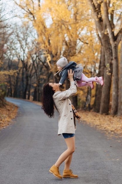 Młodej kobiety mama bawić się z małą córką przy jesień parka drogą