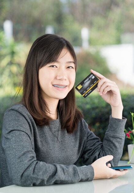 Młodej kobiety obsiadanie pokazuje kredytową kartę