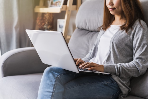 Młodej kobiety obsiadanie przy żywym pokojem i działanie na laptopie w domu