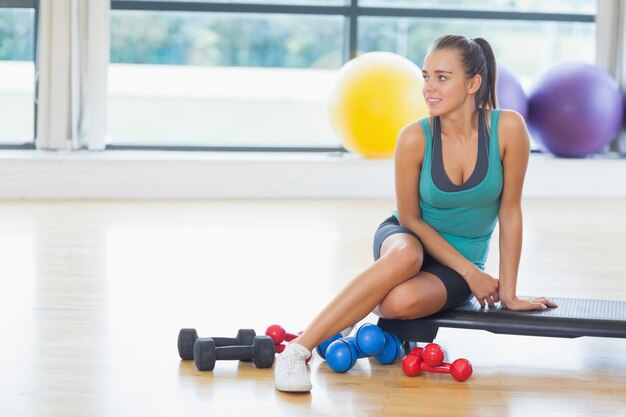 Młodej kobiety obsiadanie z dumbbells w sprawności fizycznej studiu