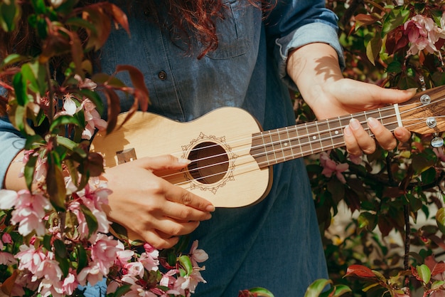 Młodej Kobiety Ręki Trzyma Ukulele Na A Kwitnące Jabłonie