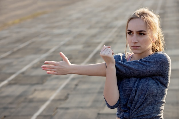 Młodej kobiety szkolenie na stadium w lecie. Sportsmenka, rozciąganie, rozgrzewka przed ćwiczeniami na zewnątrz. Zdrowy tryb życia