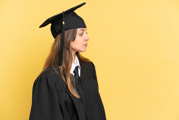 Młody absolwent uniwersytetu na żółtym tle patrząc w bok