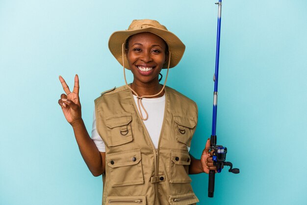 Młody african american fisherwoman trzymając pręt na białym tle na niebieskim tle Wyświetlono numer dwa palcami.