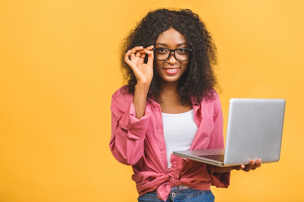 Młody Afroamerykanin czarny pozytywny fajna dama z kręconymi włosami za pomocą laptopa i uśmiechnięty