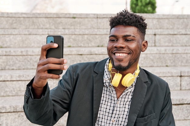 Młody Afroamerykanin używa smartfona podczas rozmowy wideo lub robi selfie