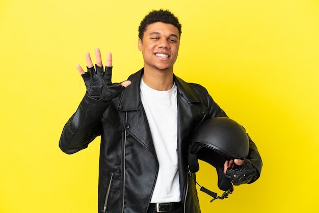 Młody Afroamerykanin z kaskiem motocyklowym na białym tle na żółtym tle liczący pięć palcami