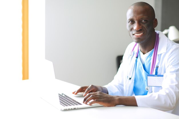 Młody afrykański lekarz pracujący na laptopie przy biurku Lekarz w miejscu pracy