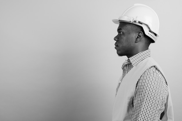 młody afrykański mężczyzna robotnik budowlany przed białą ścianą. czarny i biały