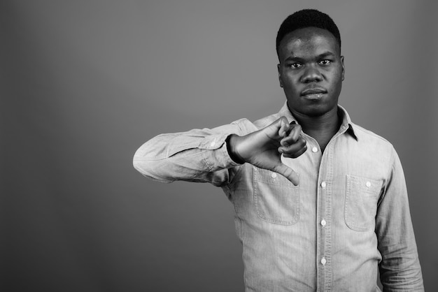młody afrykański mężczyzna ubrany w dżinsową koszulę przed szarej ścianie. czarny i biały