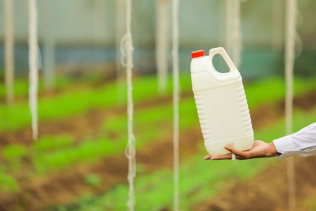 Młody Agronom Trzymając W Ręku Butelkę W Szklarni