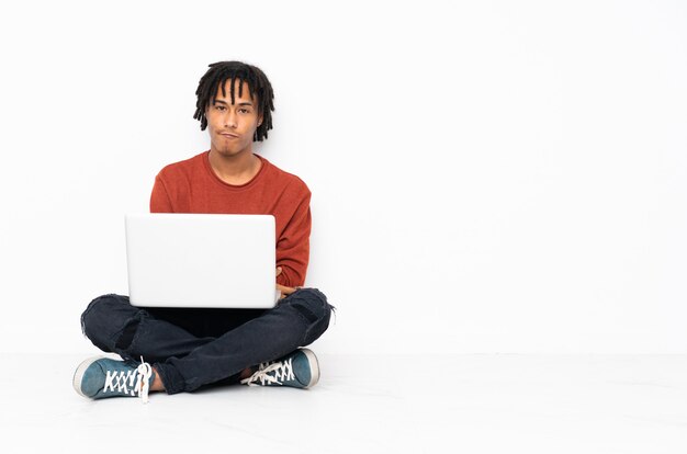 Młody amerykanina afrykańskiego pochodzenia mężczyzna obsiadanie na podłoga i działanie z jego laptopu czuć zdenerwowany