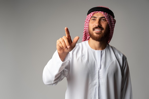 Młody Arab wskazując ręką, aby skopiować przestrzeń na szarym tle