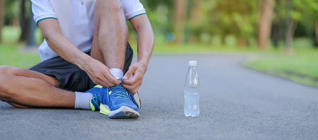 Młody atleta mężczyzna wiąże działających buty w parku plenerowym