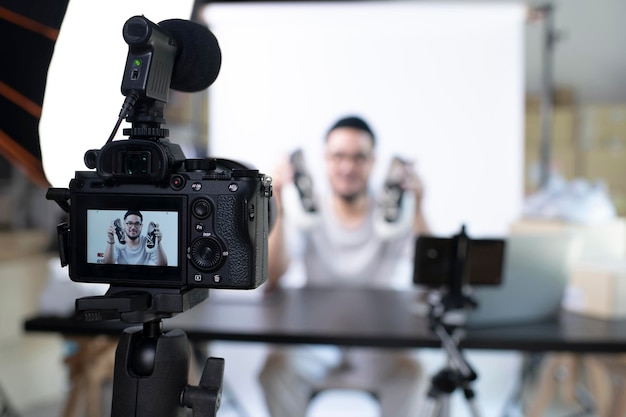 Młody atrakcyjny azjatycki mężczyzna blogger lub vloger patrzący na kamerę recenzującą produkt Nowoczesny biznesmen korzystający z mediów społecznościowych do marketingu Biznesowy wpływowy online na koncepcji mediów społecznościowych