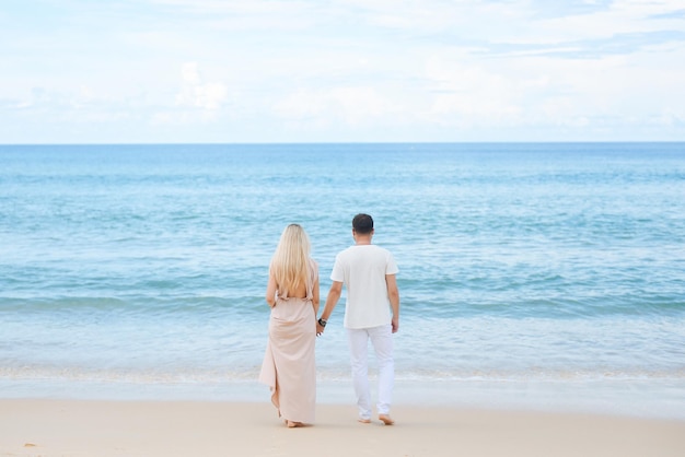 Młody atrakcyjny mężczyzna i kobieta zakochani spacerują i przytulają się na tle białego piasku i lazurowego morza Podróż poślubna