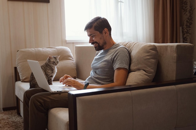 Młody atrakcyjny uśmiechnięty facet przegląda swój laptop